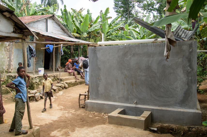 Ein Junge steht auf Haiti vor einer Zisterne