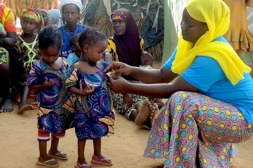 Frau misst den Arm eines Kindes in Niger