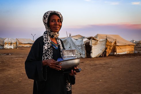 Frau im Sudan mit Artikeln des täglichen Bedarfs in den Händen