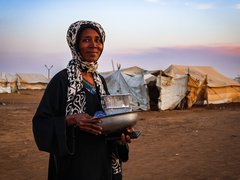 Frau im Sudan mit Artikeln des täglichen Bedarfs in den Händen