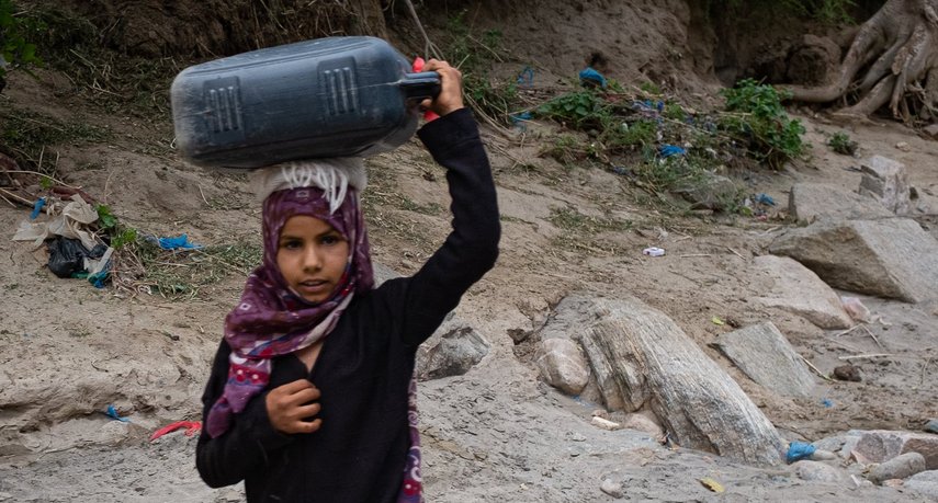 Mädchen trägt Wasserkanister auf Kopf