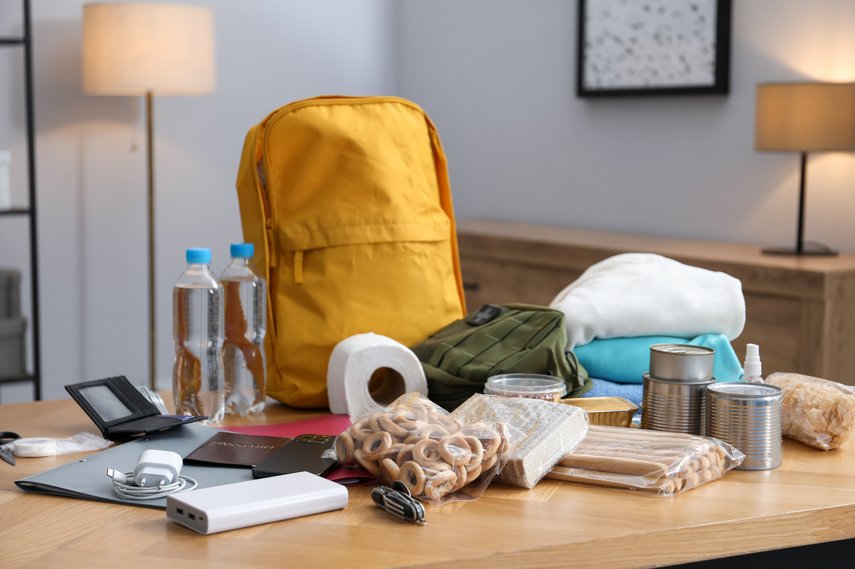 Notfall-Rucksack mit Notfallgepäck Kleiner Rucksack mit davor ausgebreitetem Notfallgepäck