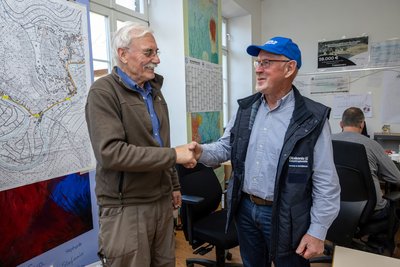 Ein Mitarbeiter der Diakonie Katastrophenhilfe und ein vom Hochwasser Betroffener schütteln Hände