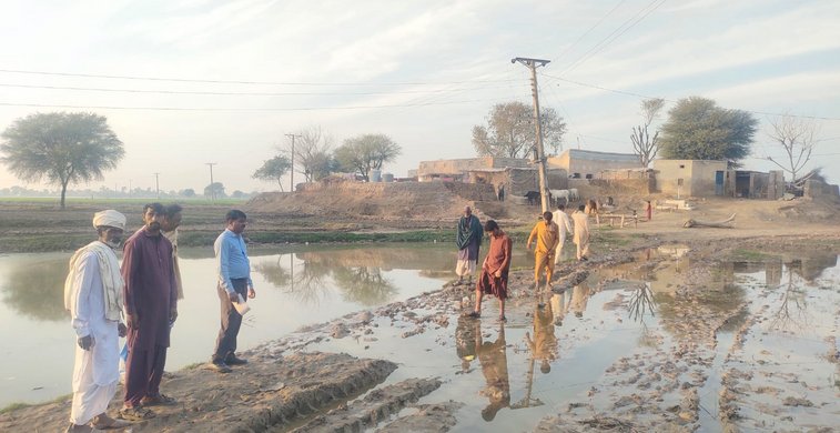 Menschen stehen in Pakistan auf ihrem überschwemmten Feld