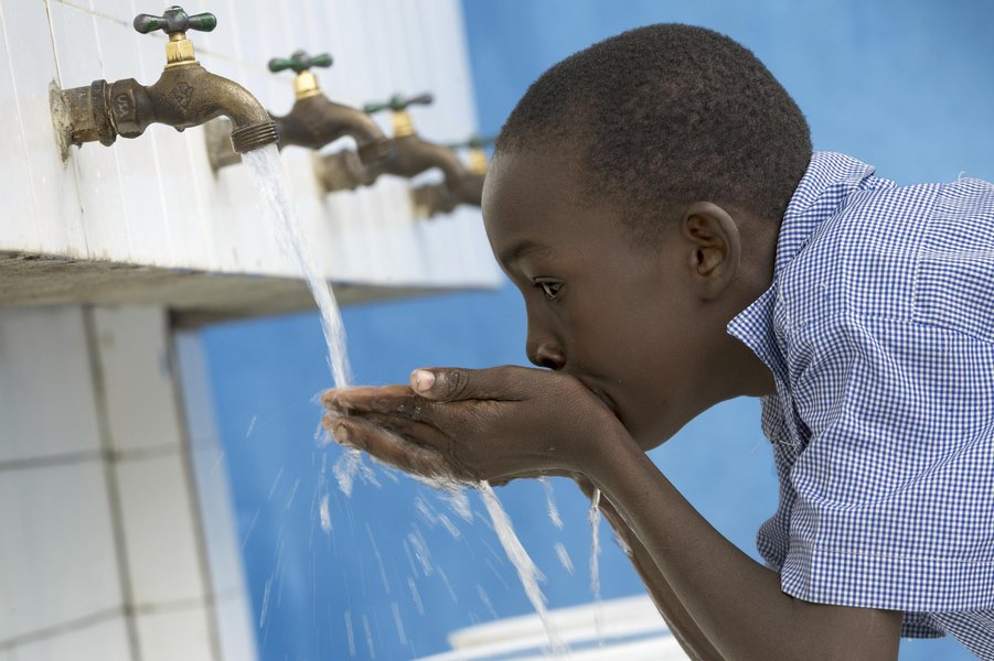 Ein Junge trinkt Wasser aus dem Hahn auf Haiti.