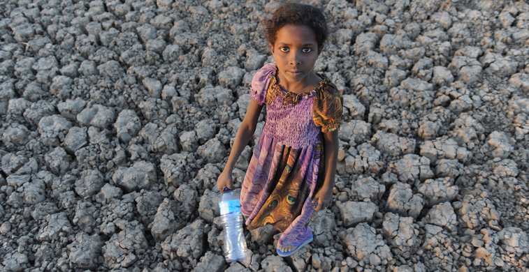 Ein Mädchen steht auf einem vertrockneten Erdboden in Äthiopien.