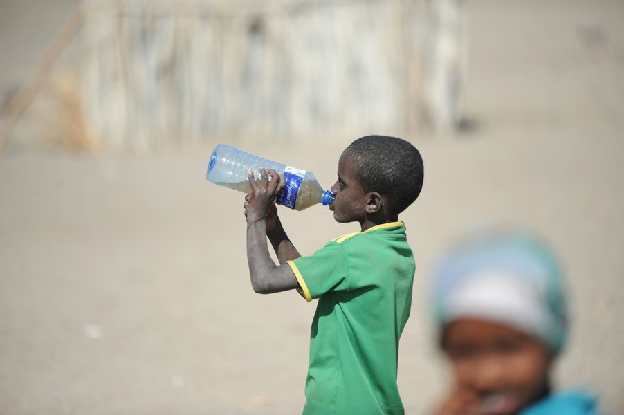 Ein Kind trinkt verschmutztes Wasser aus einer Flasche.