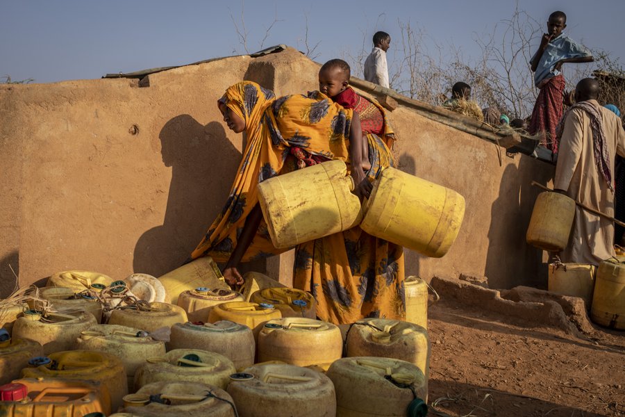Eine Frau sammelt Wasser für den Transport.