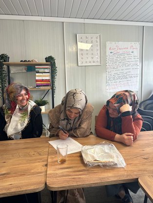 Frauen sitzen an einem Tisch und füllen eine Liste aus
