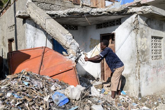 Ein Mann versucht mit einem einfachen Hammer ein Betonteil des Daches seines Hauses in Jeremie am 17.10.16 zu zerkleinern.Haiti nach dem Sturm Matthew, Oktober 2016. Foto: Thomas Lohnes fuer Diakonie Katastrophenhilfe