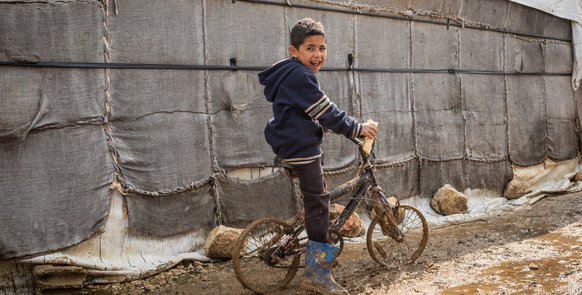Ein Junge auf einem Fahrrad im Lager in Khyara.