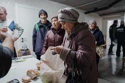 Die Bewohner erhalten Lebensmittel von der humanitären Organisation World Central Kitchen in einem Kindertagesstättenzentrum, das aufgrund der extremen Kälte und der Schäden an der Energieinfrastruktur nun als Notheizstelle und Notunterkunft genutzt wird. Projekt „Save Ukraine“. Irpin, Ukraine, Februar 2026.