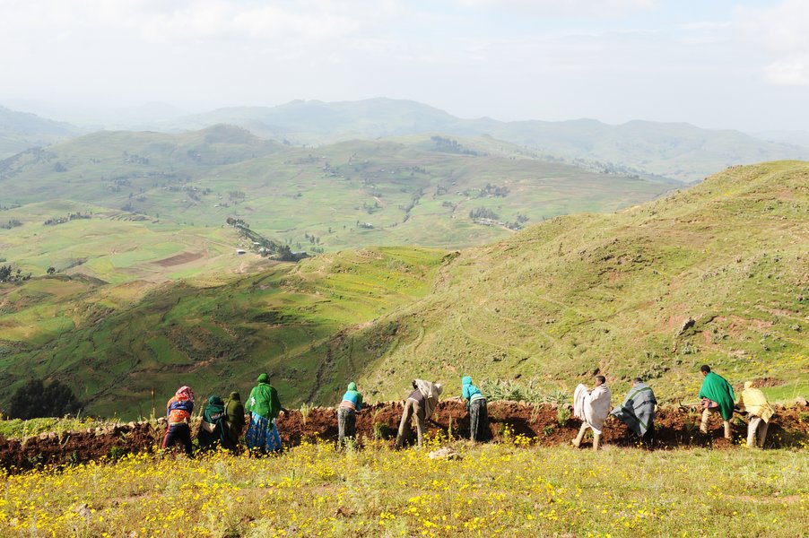 Menschen in Äthiopien vor einem Erdhügel.