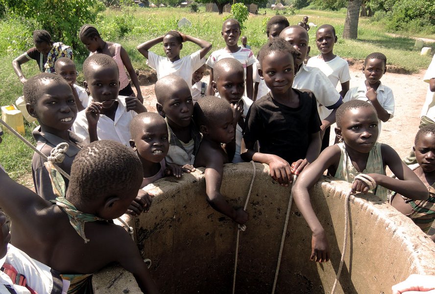Kinder versammeln sich an einer Wasserstelle.