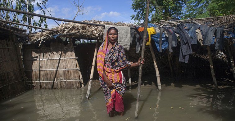 Eine Frau watet durch die Fluten in Bangladesch.