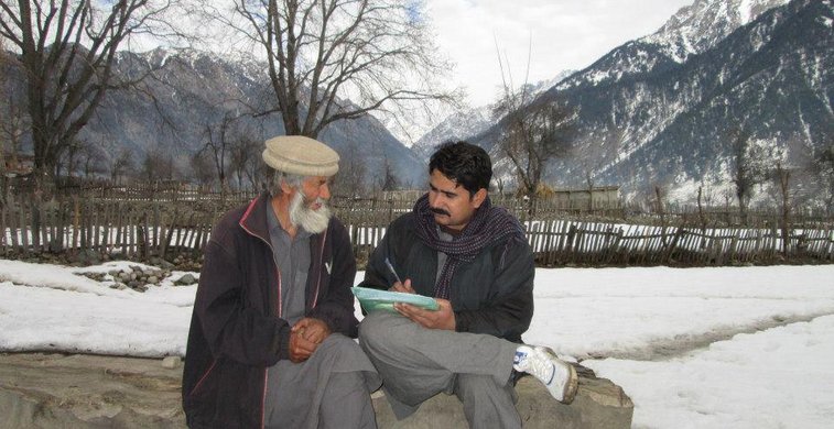 Zwei Pakistaner sitzen auf einem Stein im Schnee