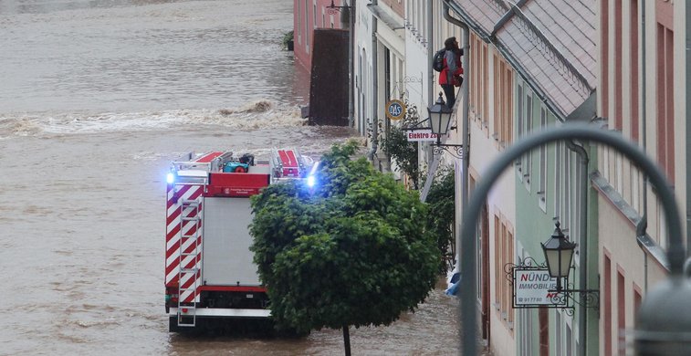 Feuerwehr fährt durch überflutete Straße