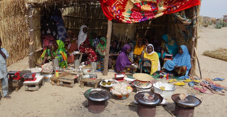 Frauen sitzen im Tschad vor einer Kochstelle.